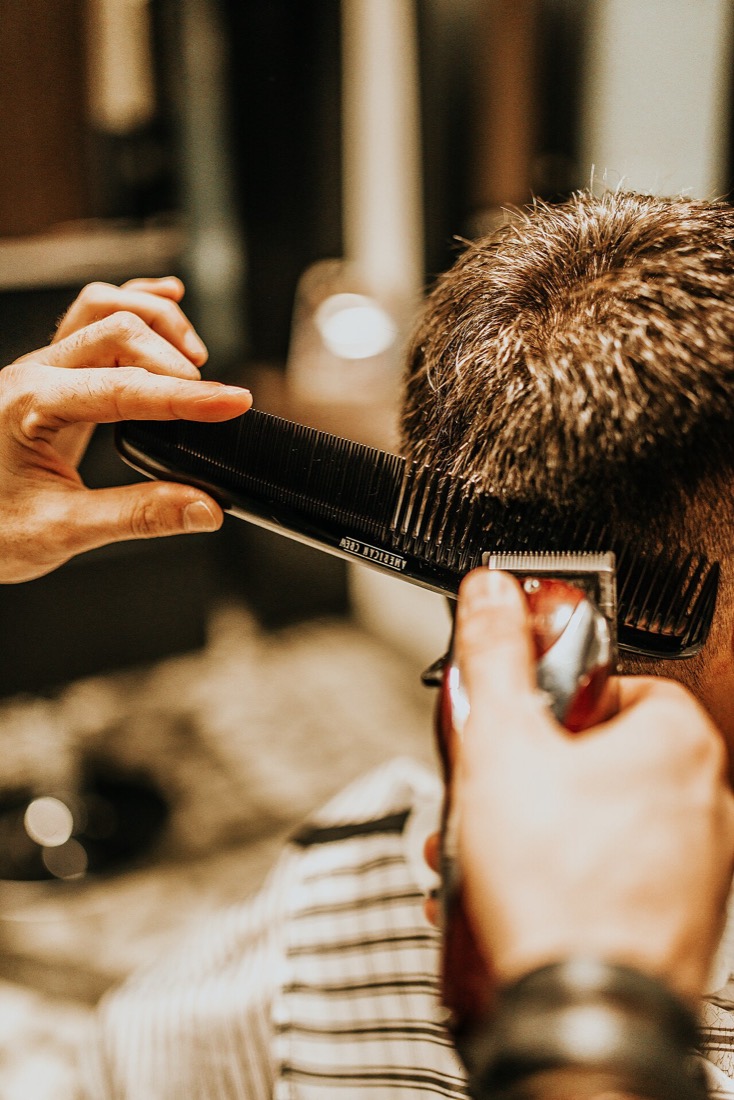 Barber finishing a precise fade with clippers and comb